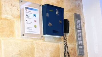 A blue security box with a keypad and a telephone on a beige wall.