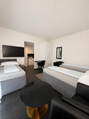 A modern hotel room with two beds, a flat-screen TV, a small desk, and a round table. - Seefeld Residenz GmbH (Zürich)