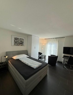 Une chambre d’hôtel moderne équipée d’un lit, d’un bureau, d’une chaise et d’un téléviseur.