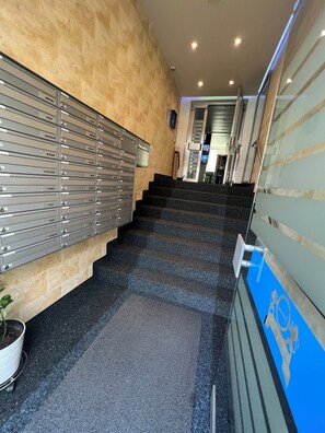 A staircase with metal storage units on the left and a blue sign with a logo on the right. - Seefeld Residenz GmbH (Zürich)