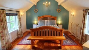 Un dormitorio con cama de madera, una araña, decoraciones en forma de corazón y una ventana con cortinas.