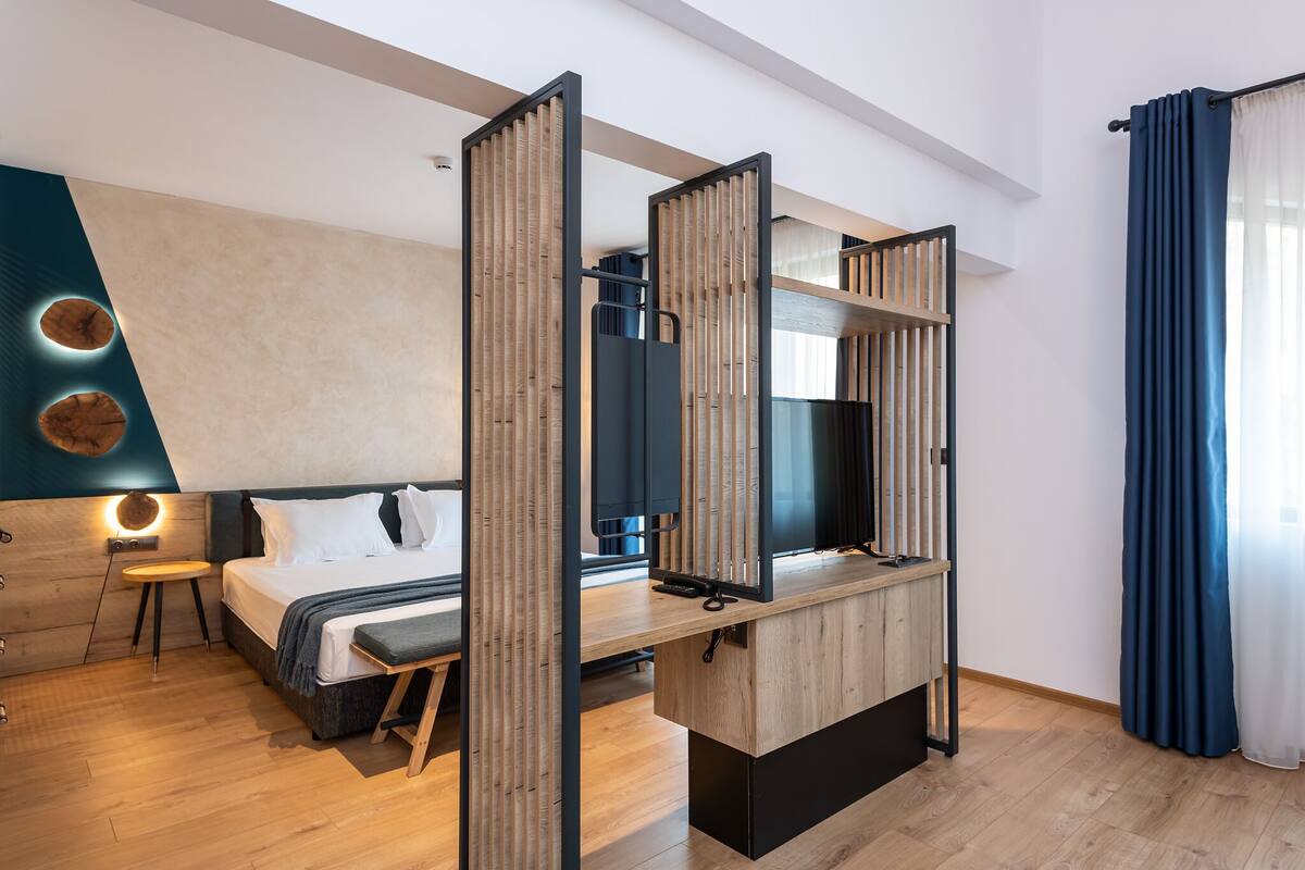 Une chambre d’hôtel moderne équipée d’un lit, d’une table de chevet et d’un téléviseur.