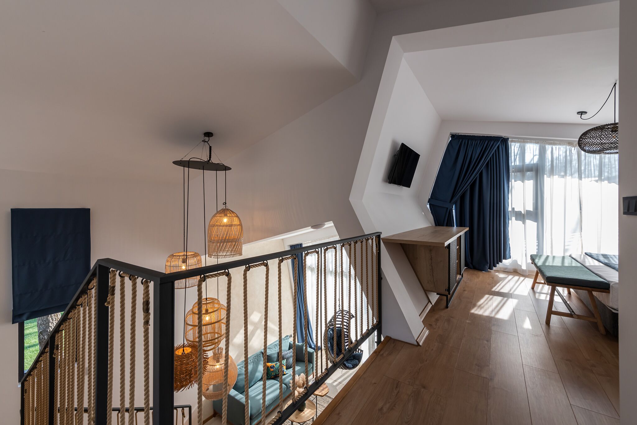 Una habitación estilo loft moderna con una escalera, un sofá, una zona de comedor y un televisor montado en la pared.