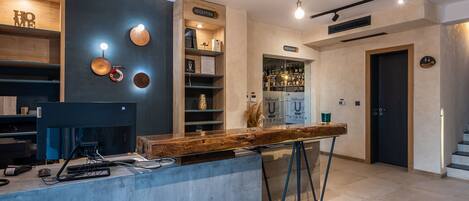 Un área de recepción moderna con un mostrador de madera, una computadora y un letrero que indica un restaurante.