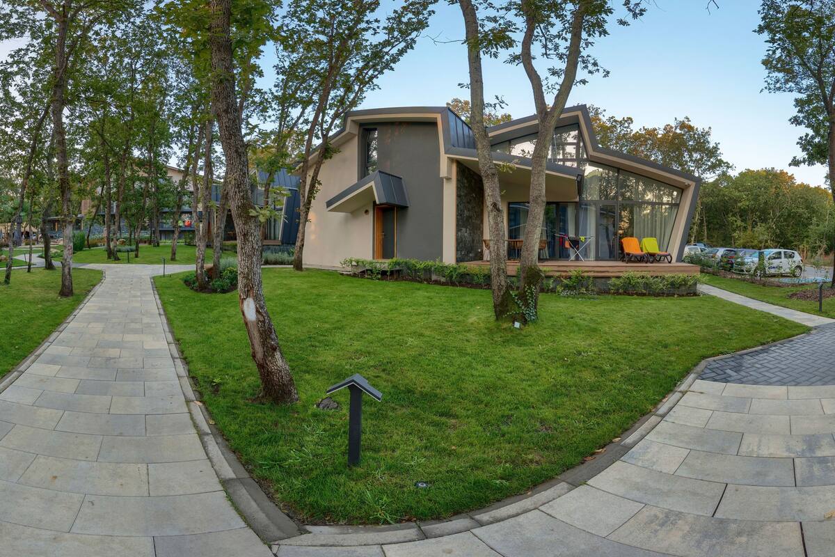 Un bâtiment moderne doté d’un toit plat, entouré d’une pelouse bien entretenue et d’arbres.