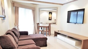 Een moderne woonkamer met een bruine hoekbank, een eettafel met stoelen en een wandgemonteerde flatscreen-tv.
