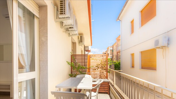 A narrow balcony with a table and chairs, air conditioning units, and a wooden fence. - Anita Apartment (Noto)