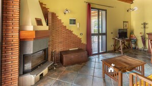 A cozy living room with a fireplace, a wooden table, and a suitcase, suggesting a homey atmosphere. - Garden Chich (Noto)