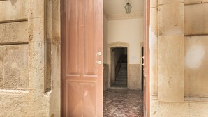 An open wooden door leading to a hallway with a tiled floor and a staircase.