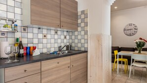 A modern kitchen with a tiled backsplash, wooden cabinets, and a dining area with a table and chairs.