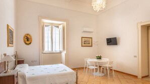 A bedroom with a bed, a desk, a chair, a table, a TV, and a window. - Liberty Guest House (Avola)