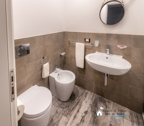 A modern bathroom with a toilet, bidet, and sink. - Magnolia (Avola)