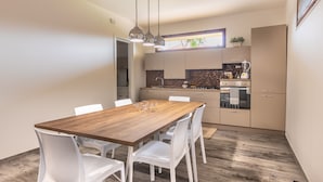 A modern kitchen with a wooden dining table and white chairs.