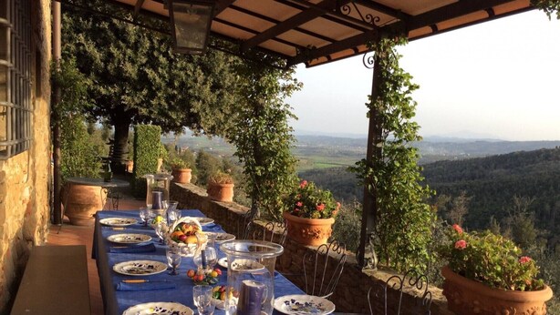 A long table set for dining with a view of the countryside.