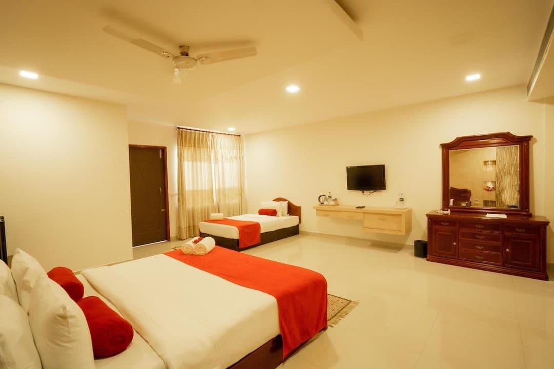 Habitación de hotel con cama, escritorio, espejo y televisión.