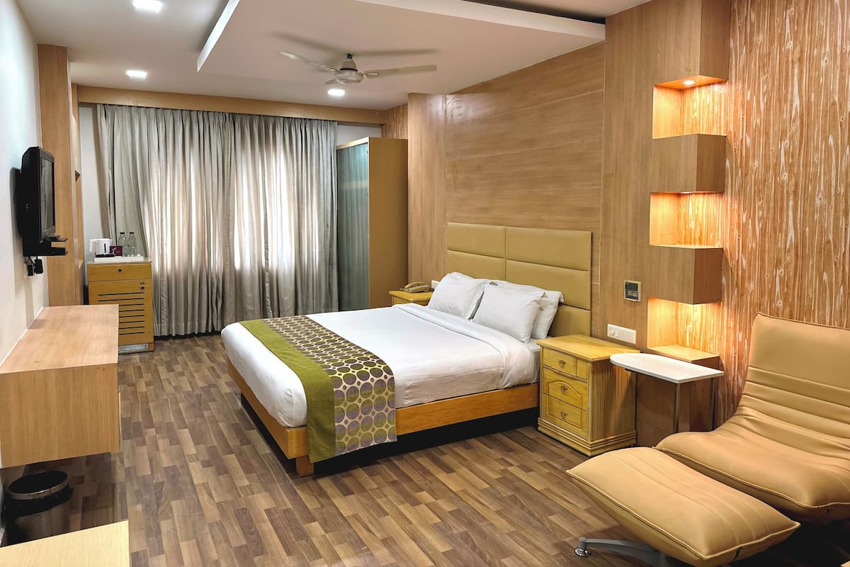 Une chambre d’hôtel équipée d’un lit, de tables de chevet, d’un bureau, d’une chaise, d’une télévision et d’un rideau.