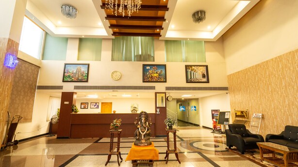 Un vestíbulo de hotel con mostrador de recepción, una estatua, zona de estar y obras de arte en las paredes.