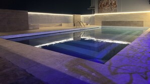 Una piscina al aire libre con solárium de piedra y un mural en la pared.
