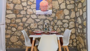 Un mur de pierres avec une table dressée pour deux personnes, agrémentée d’une bouteille et de verres.