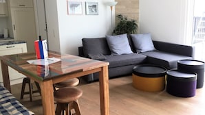 Una sala moderna con una mesa de comedor de madera, un sofá gris y otomanas negras.