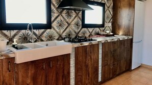 A kitchen with a double sink, wooden cabinets, a gas stove, and a black range hood.