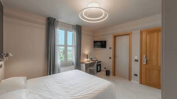 Ein modernes Hotelzimmer mit einem großen Bett, einem Schreibtisch mit Stuhl, einem Fernseher und einer Holztür.