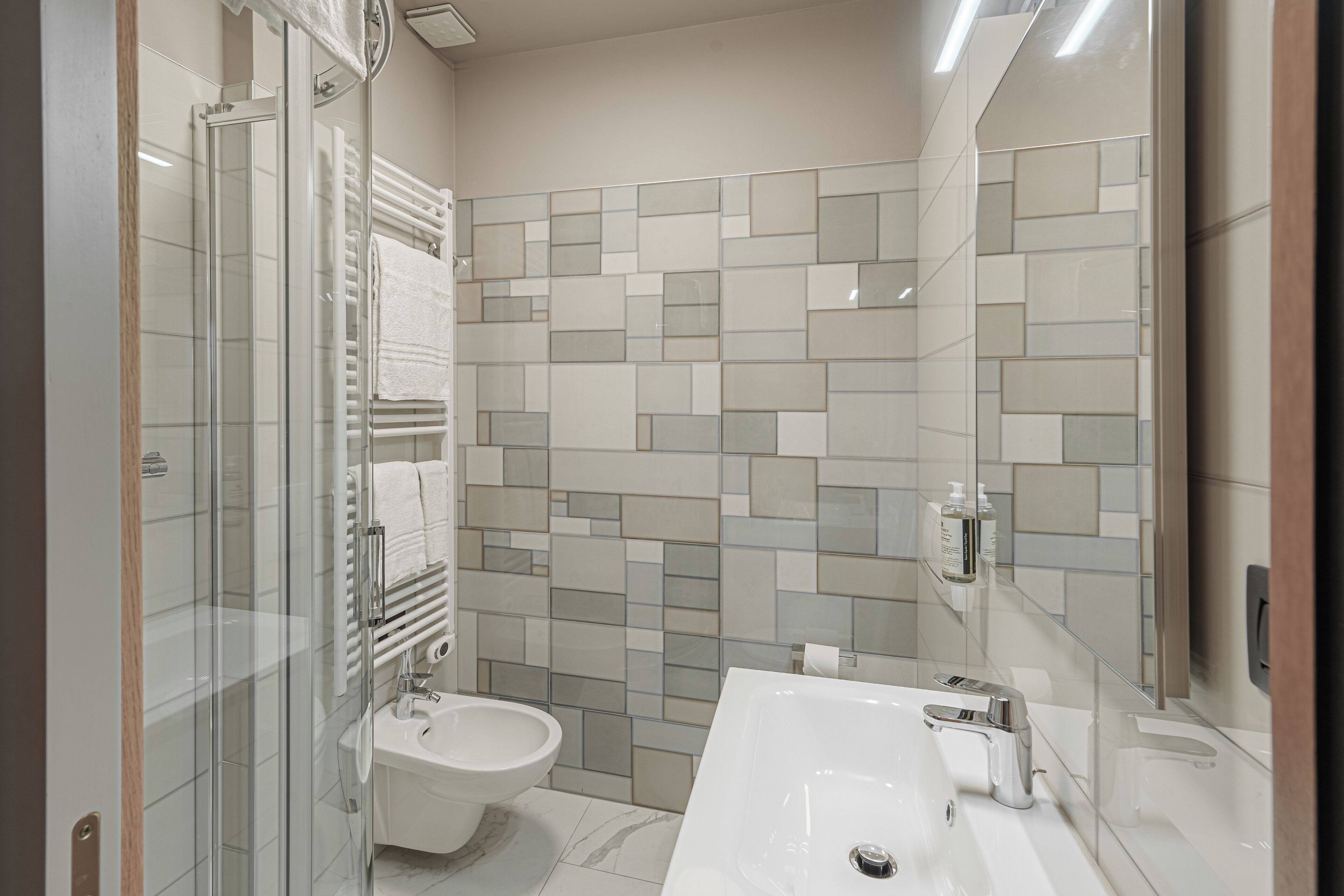 Un baño moderno con cabina de ducha de vidrio, un bidé y un lavabo grande con espejo.