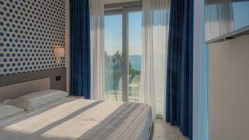 Een hotelkamer met een bed, een behang met patroon, uitzicht op het groen en een televisie aan de muur.