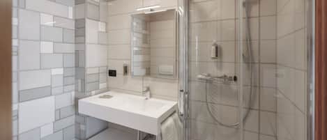 A modern bathroom with a glass-enclosed shower, a white sink, and a mirror above it.