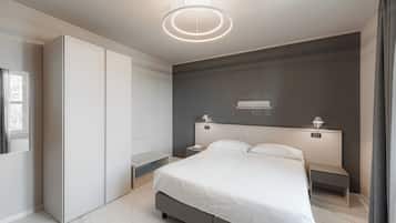 A modern bedroom with a large bed, bedside tables, a wardrobe, and a ceiling light fixture.