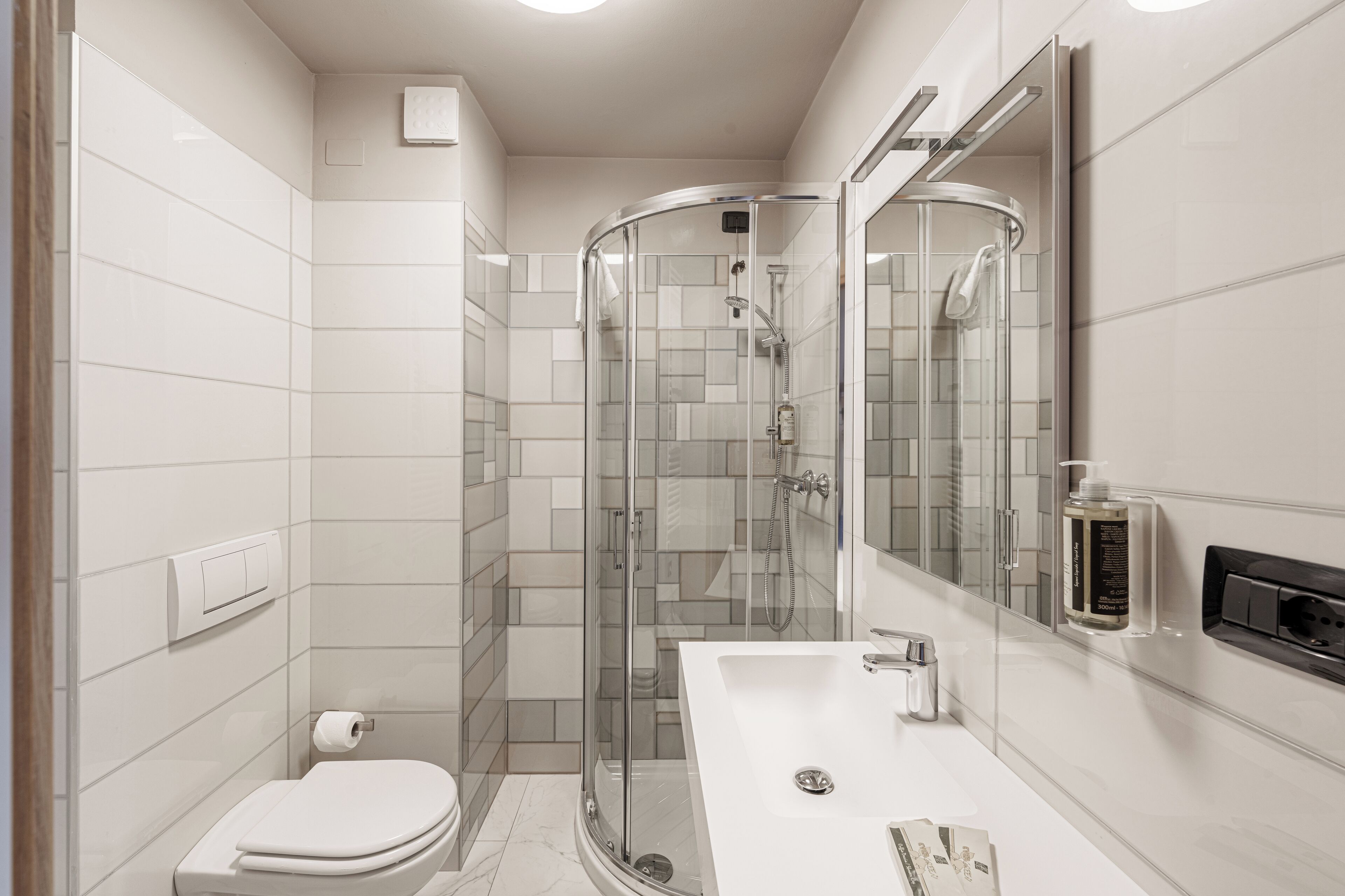 A modern bathroom with a glass-enclosed shower, a white sink, and a toilet.
