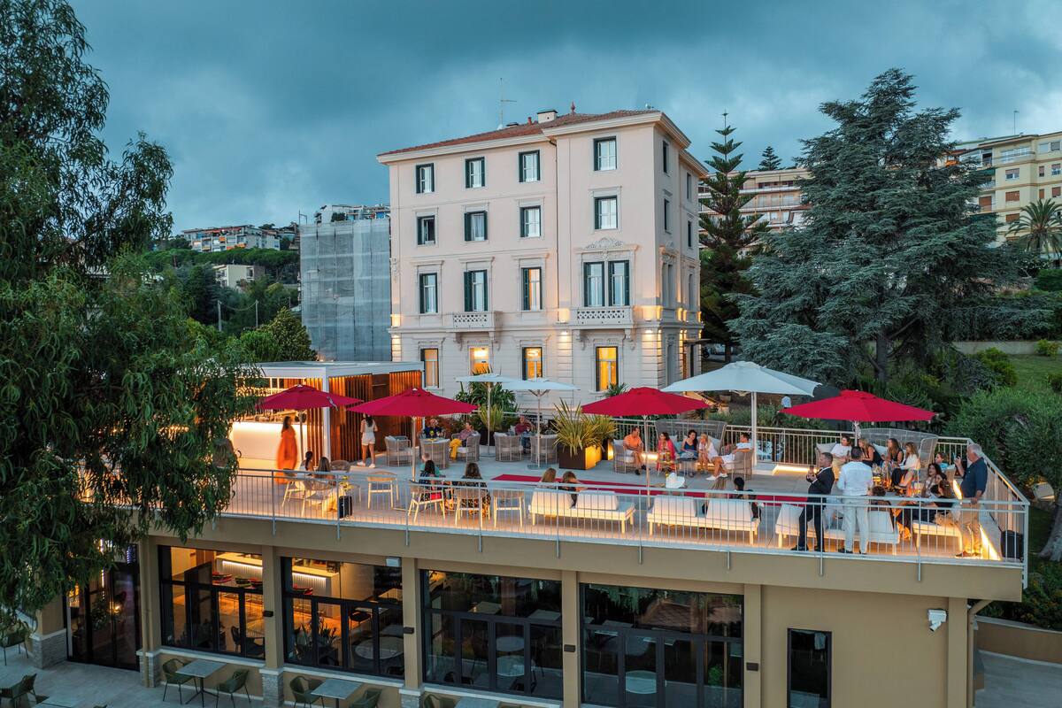 A hotel with outdoor seating, multiple floors, and a balcony with umbrellas.