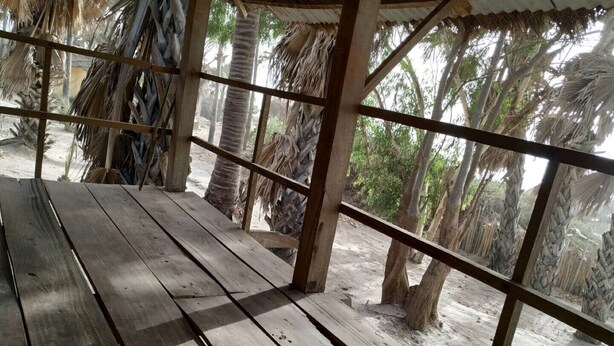 A wooden deck with a thatched roof, surrounded by palm trees. - Unspoiled South Gambian Paradise '' VIP Treehouse '' (Kartung)