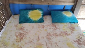 A bed with a floral bedspread and two pillows with a sun design. - Unspoiled South Gambian Paradise '' VIP Treehouse '' (Kartung)