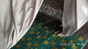 A room with a bed covered by a patterned blanket, a woven mat, and a curtain partially drawn. - Unspoiled South Gambian Paradise '' VIP Treehouse '' (Kartung)