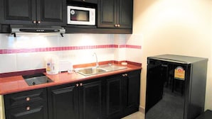 A kitchen with black cabinets, a microwave, a sink, and a coffee maker. - Jomtien Beach Sea View Studio (Pattaya)