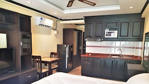 A compact hotel room with a bed, a small kitchenette, a dining area, and a TV. - Jomtien Beach Sea View Studio (Pattaya)