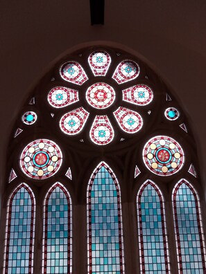 A large arched stained glass window with intricate designs and multiple smaller windows below.