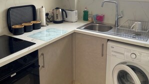 Una cucina compatta con lavatrice, tostapane e macchina del caffè.