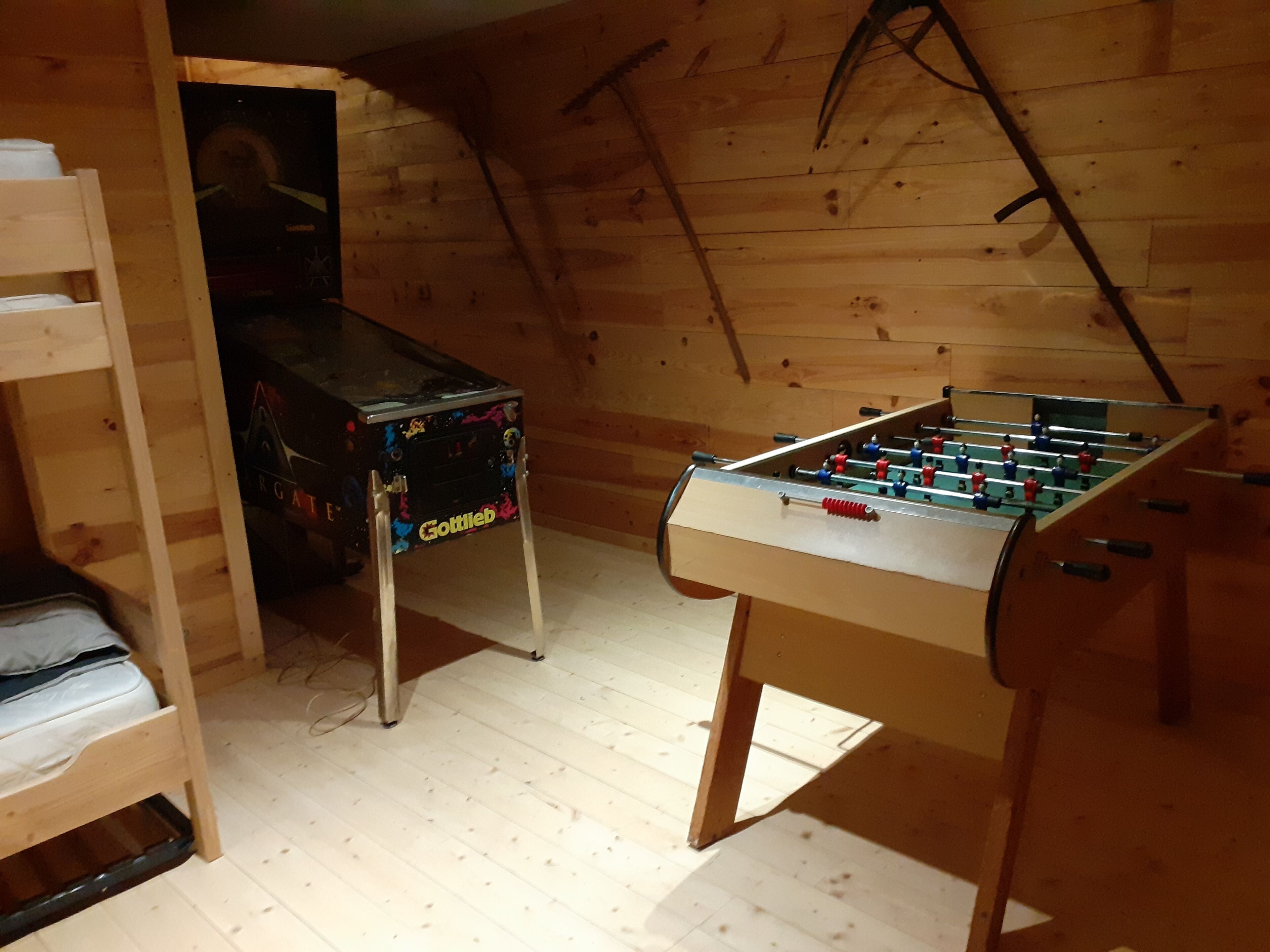 Une pièce avec une table de baby-foot, une petite table ornée d’un logo et un lit avec une tête de lit en bois.
