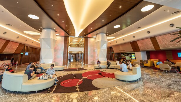 Un'ampia hall dall'arredamento moderno, con un'area salotto centrale dotata di divani e una moquette decorata.