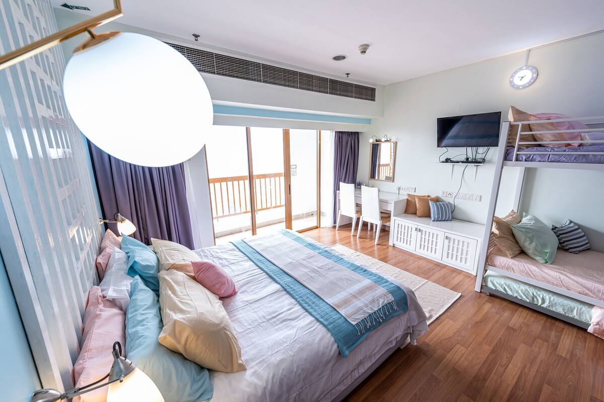 Ein Schlafzimmer mit Etagenbett, Schreibtisch, Stuhl, Fernseher und großem Fenster.