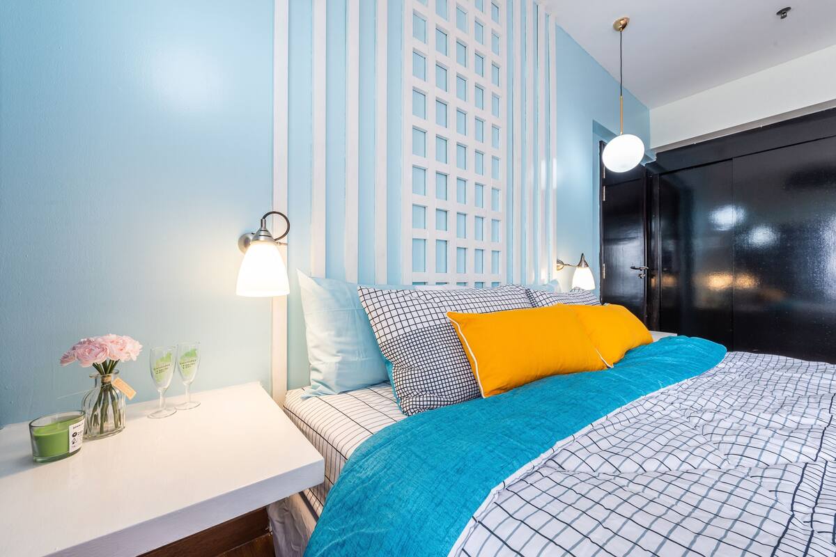 Ein ordentlich eingerichtetes Schlafzimmer mit Bett, Nachttisch und einer Wandleuchte.