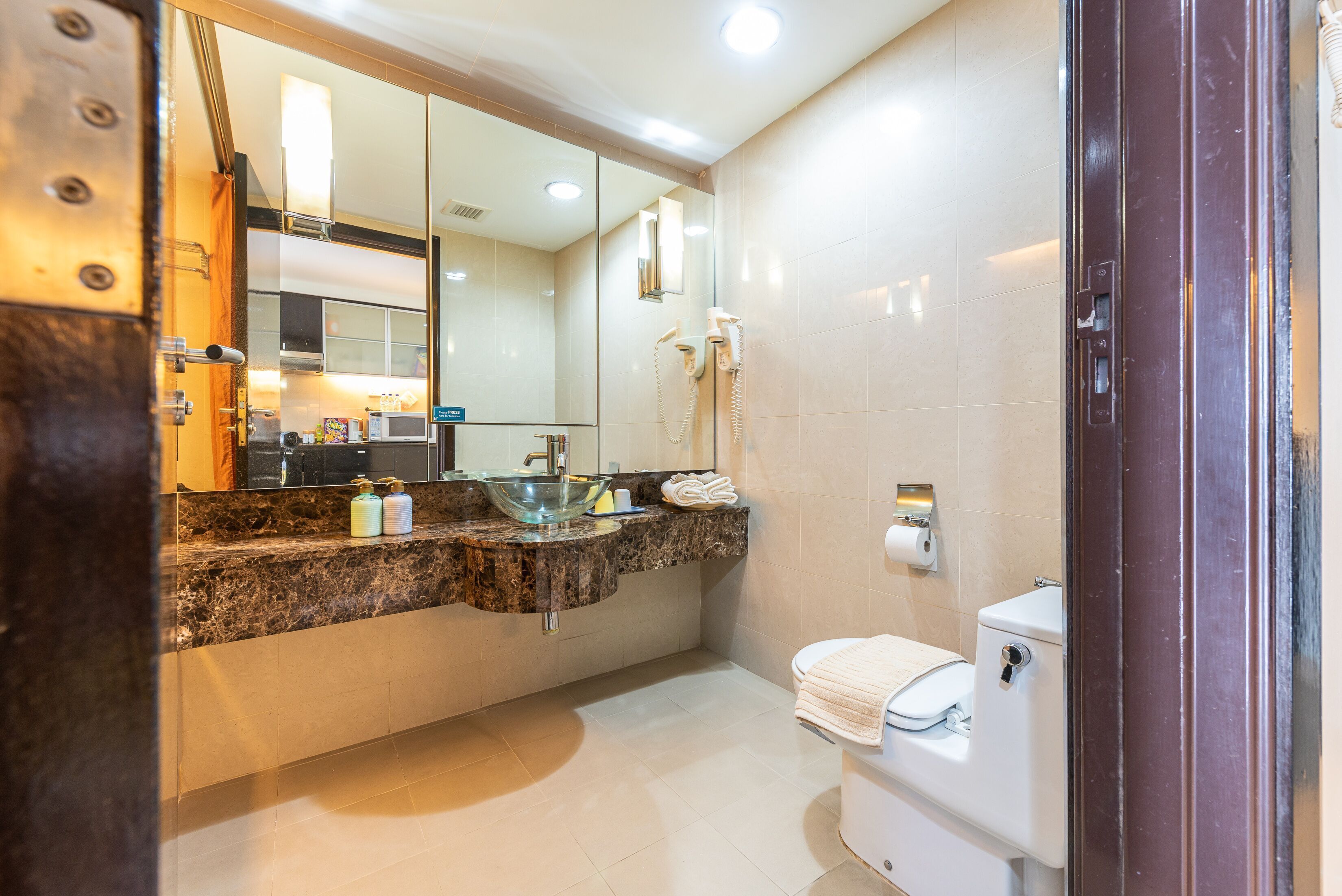 A modern bathroom with a glass bowl sink, a white toilet, and a large mirror.