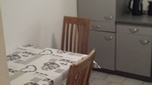 A small kitchen with a table and chairs, a cabinet, and a coffee maker. - Monteurzimmer & Ferienwohnung G. Klement (Herrieden)