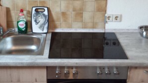 A kitchen with wooden cabinets, a stainless steel sink, a gas stove, and a built-in oven. - Monteurzimmer & Ferienwohnung G. Klement (Herrieden)