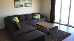 Ein modernes Wohnzimmer mit einem Ecksofa, einem Couchtisch und einem großen abstrakten Gemälde an der Wand.