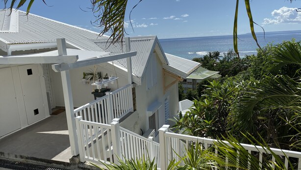 A white building with a balcony overlooking the ocean. - Magnifique appartement vue mer 180° - Hauteur anse Des Rochers - Avec Cuve Eau (Saint-François)