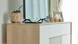 A wooden and white cabinet with a flat-screen TV, a small potted plant, and a framed photo. - Domitys Emerald Haven (Antwerp)