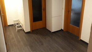 A room with wooden doors, a white refrigerator, and a small white shelf.